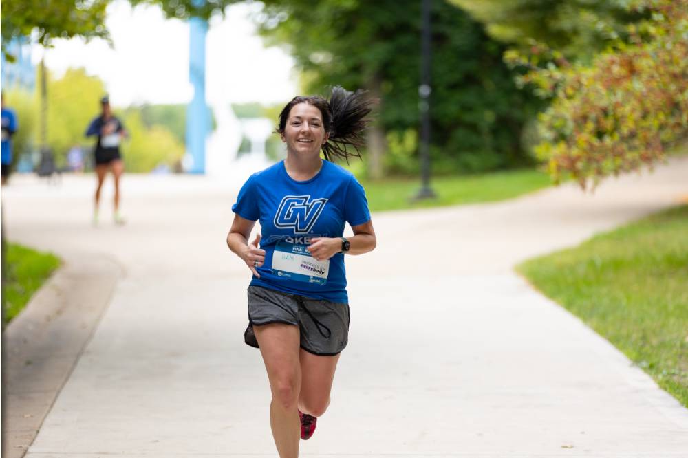Participant in blue shirt running through campus